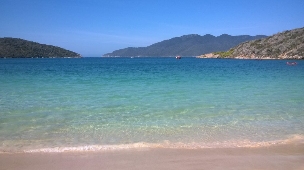 Praia do Forno em Arraial do Cabo em dia de sol com o mar azul cristalino